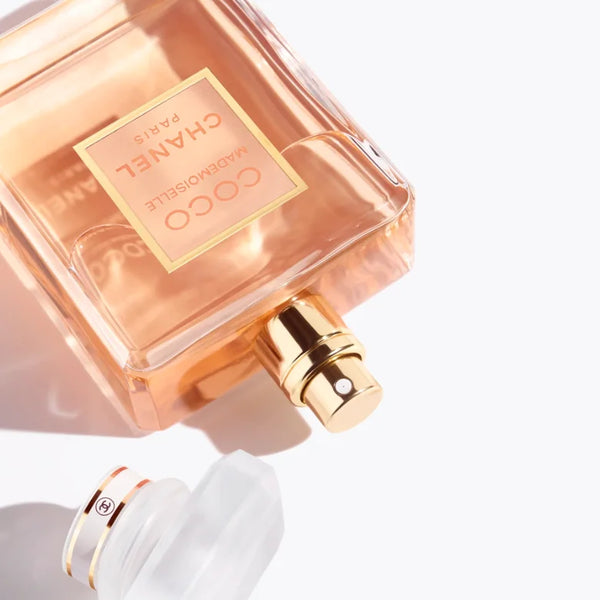 Chanel eau de parfum bottle close-up with gold spray pump and peach-pink glass