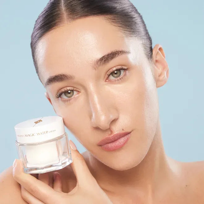 Skincare model holding Charlotte Tilbury Magic Water Cream jar at cheek level