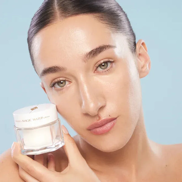 Skincare model holding Charlotte Tilbury Magic Water Cream jar at cheek level