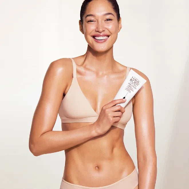 Charlotte Tilbury Magic Body Cream 200 ml tube held by smiling woman