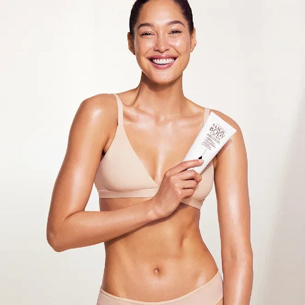 Charlotte Tilbury Magic Body Cream 200 ml tube held by smiling woman