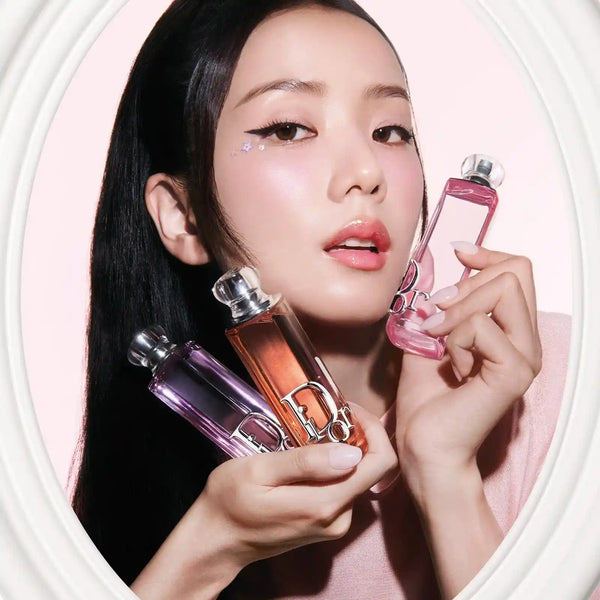 Woman holding rosy pink eau de parfum bottle with silver cap near her face