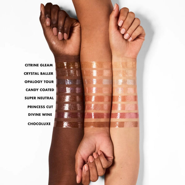 Multiple lip oil shimmer shades swatched on skin, from brown to pink and berry