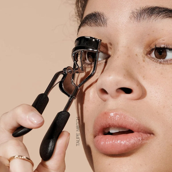 Elf Pro eyelash curler in use near eye; curved clamp with black pads and handle