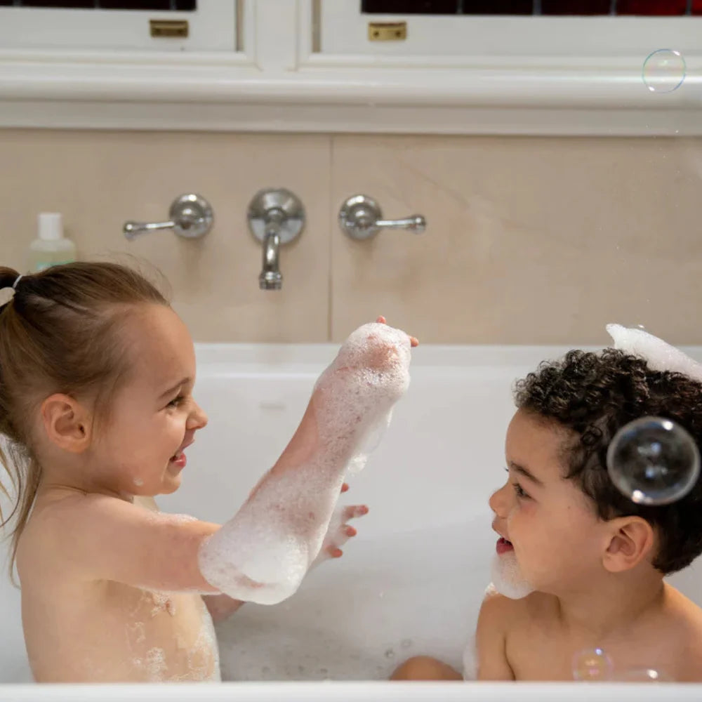 Children bathing with foam bubbles in a tub, using baby bubble bath