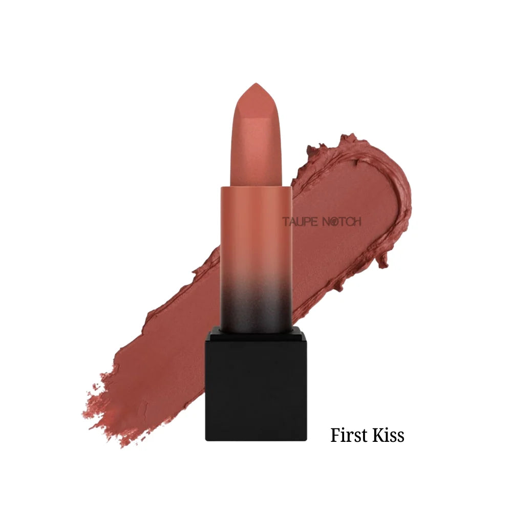 Matte lipstick bullet with muted rose-brown shade on lip swatch, “First Kiss” label