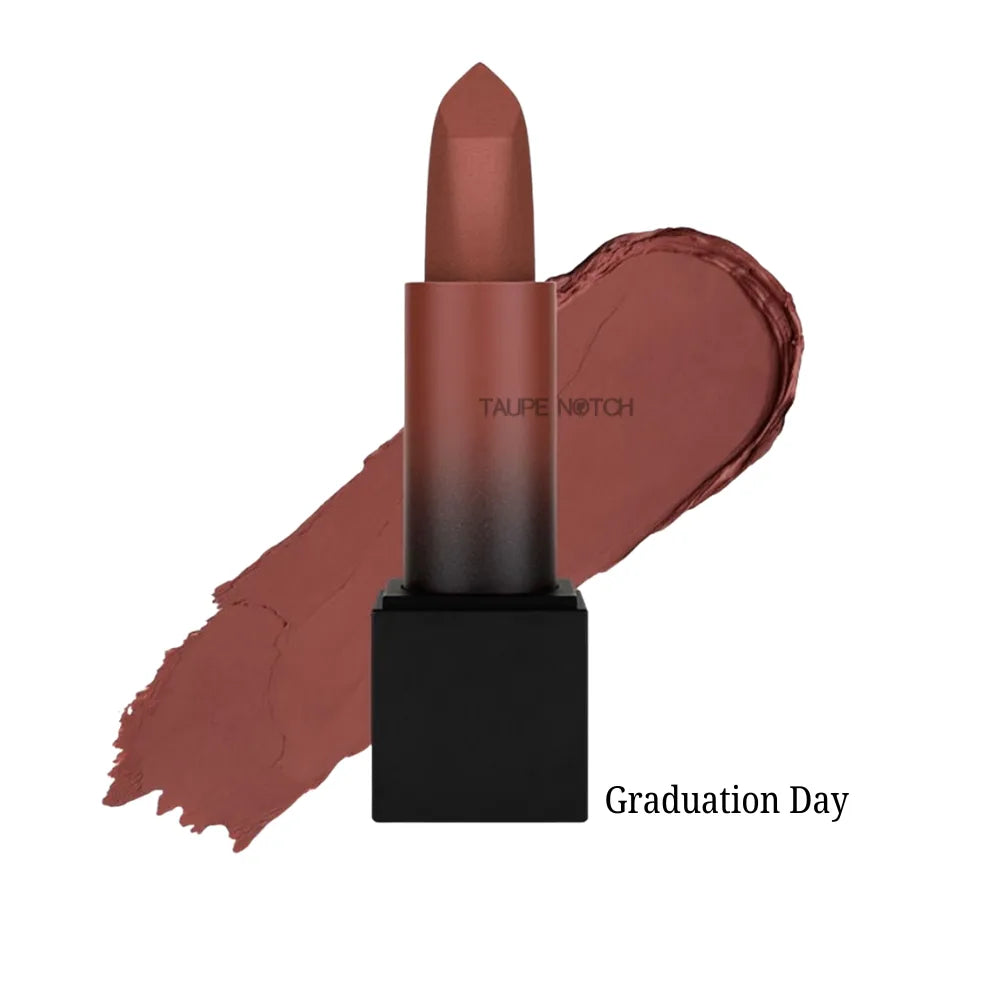 Matte lipstick bullet with warm brick-brown shade on lip swatch, “Graduation Day” label