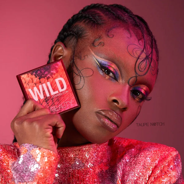 Wild Obsessions eyeshadow palette held next to model with colorful, shimmery eye makeup