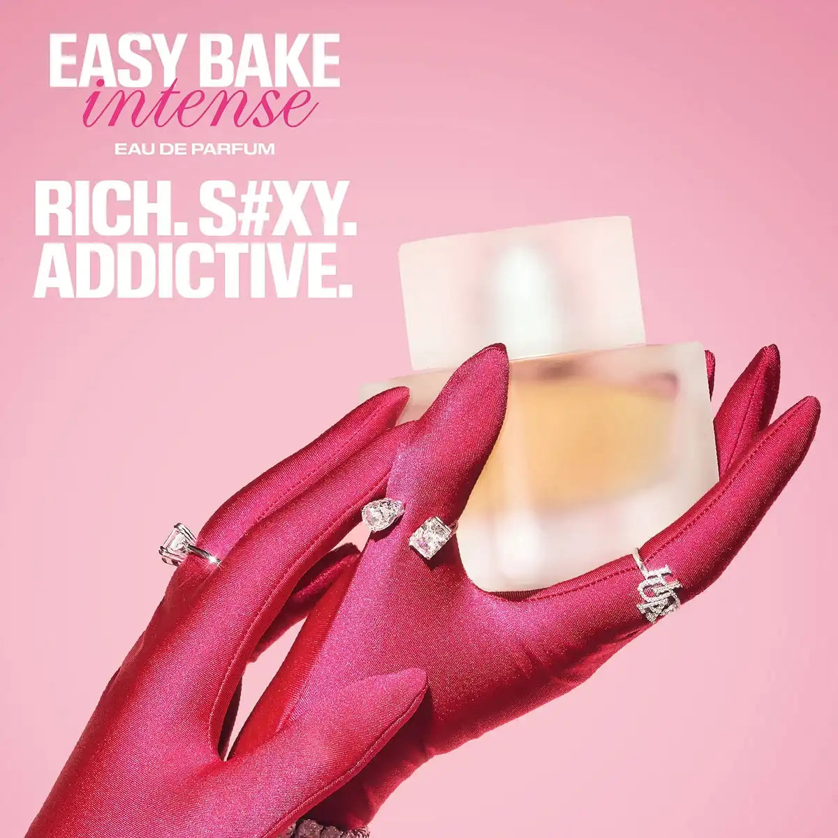 Huda Beauty Easy Bake Intense EDP - 50ml held by a hand in a red glove with text on a pink background