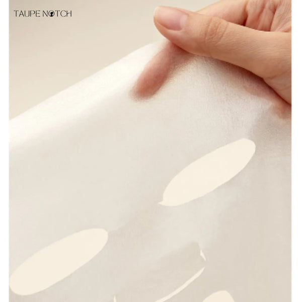 Sheet mask being smoothed onto skin by fingers, pale cream sheet
