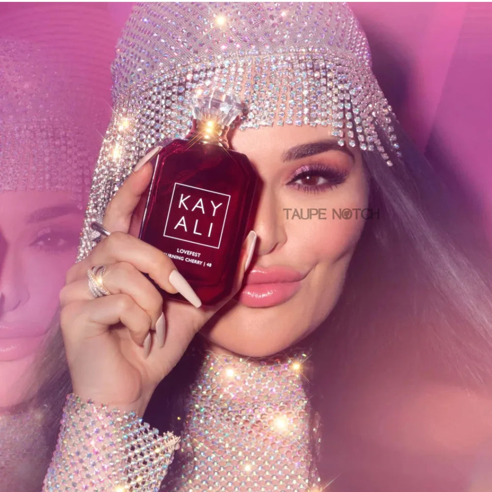 Kayali Lovefest Burning Cherry eau de parfum bottle held near face, dark maroon glass