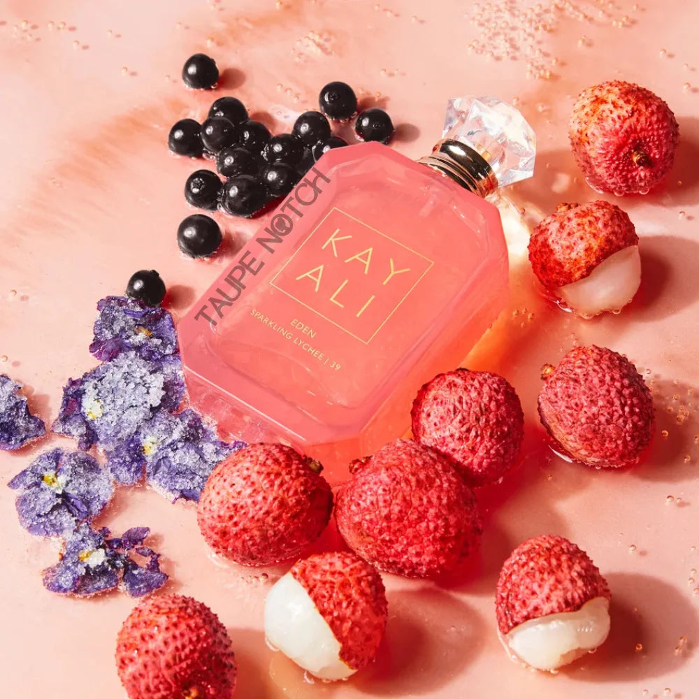 Kayali Eden Sparkling Lychee eau de parfum bottle amid fruits and berries