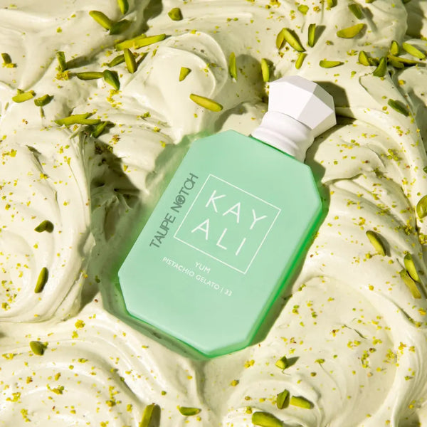 Mint green eau de parfum bottle on whipped cream with pistachio pieces