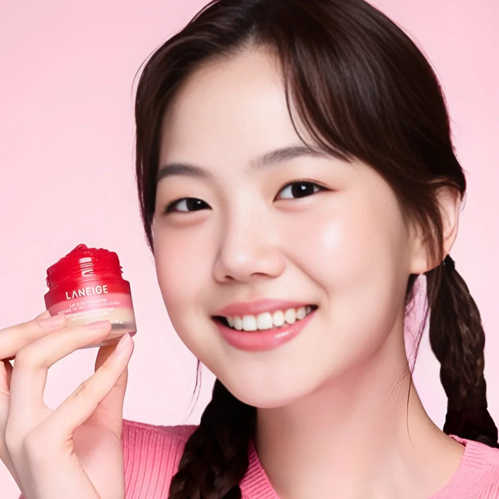 Lip Sleeping Mask jar held near face, pink container with logo.