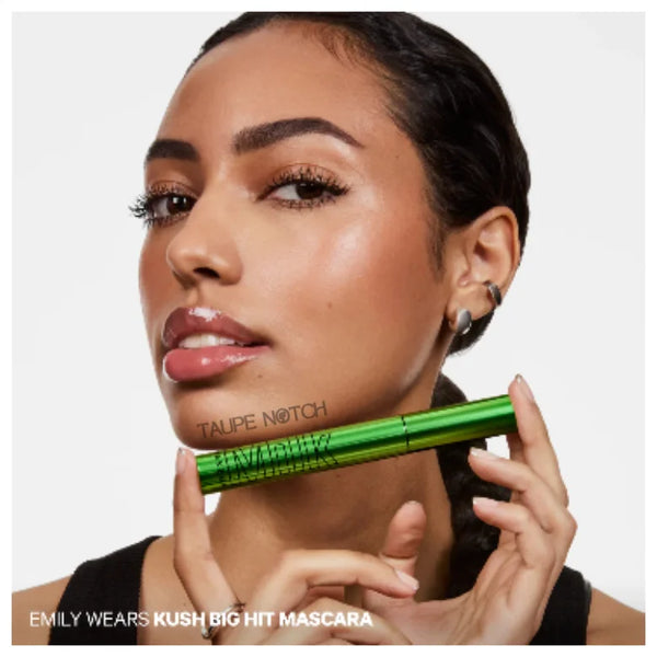 Green mascara tube with wand held near face, black cap