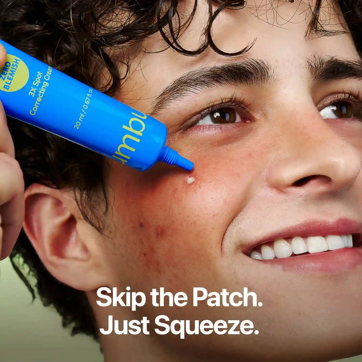 Close-up of a person applying a blue tube of blemish remover to their cheek, with the text 'Skip the Patch. Just Squeeze.