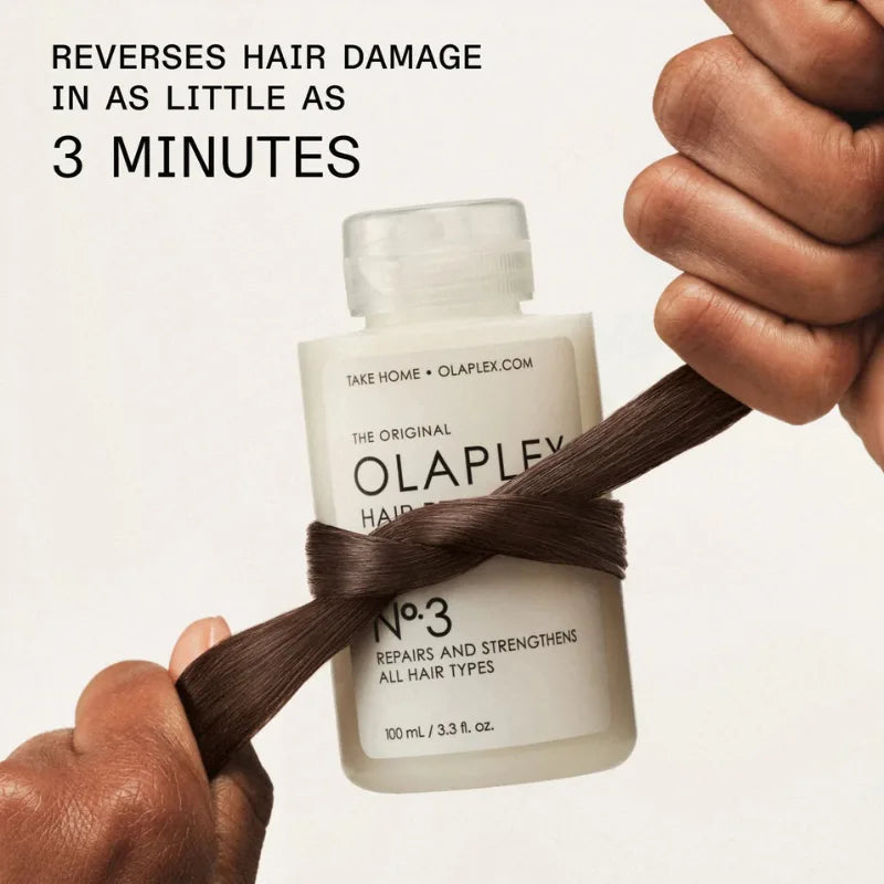 Hair perfector bottle with white label, shown with dark hair strand between fingers