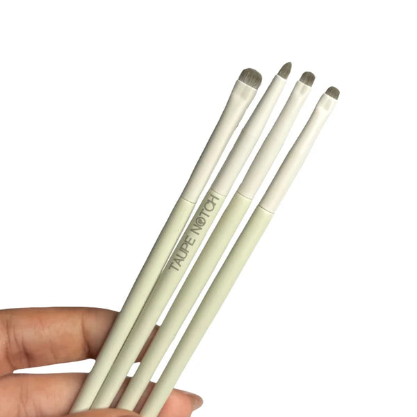 Eye brush set of four slim brushes with taupe bristles, held in hand