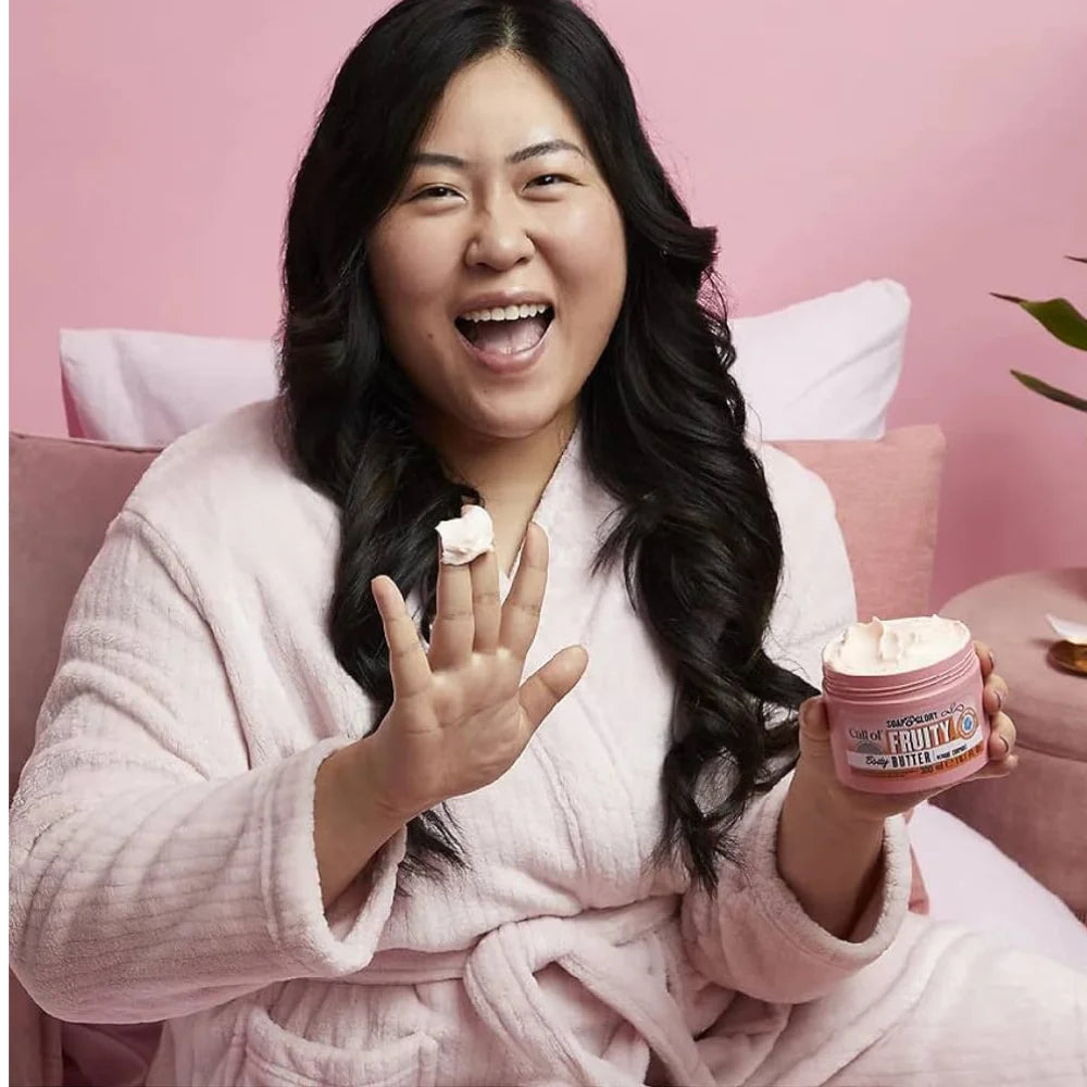 Pink body butter jar held in hand, round label and gold seal