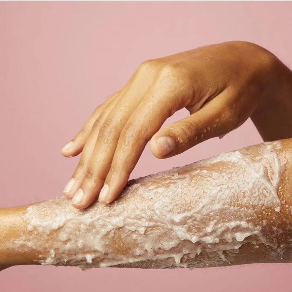 Body scrub on arm with foamy cream texture, hands rubbing