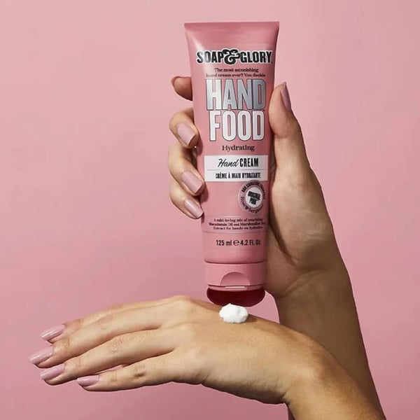 Pink hydrating hand cream tube held above back of hand with dollop applied, 125 ml