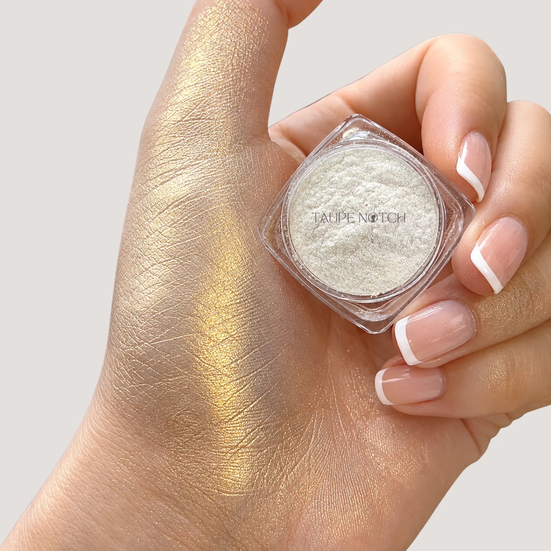 Taupe Notch loose highlighter pigment in clear compact, swatched on hand