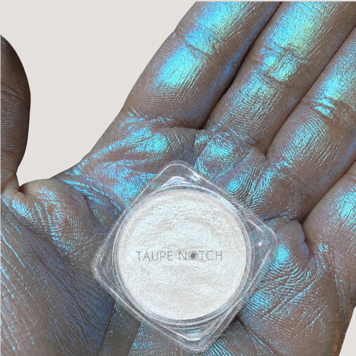 Taupe Notch loose highlighter and pigment jar on palm with shimmering silver powder