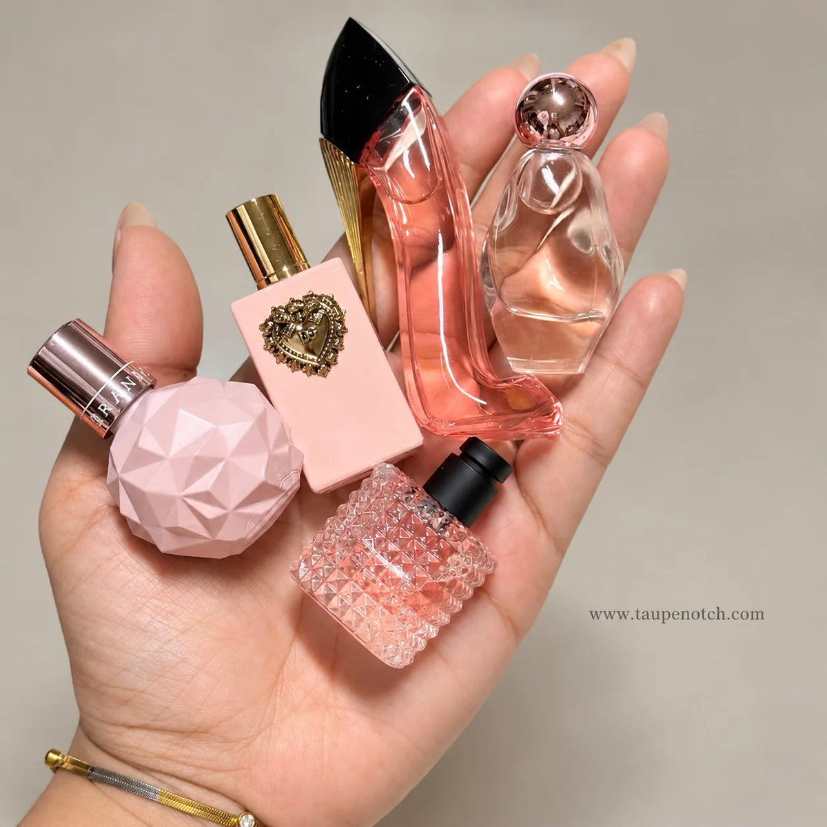 Mini perfume gift set with pink and clear bottles, held in a hand