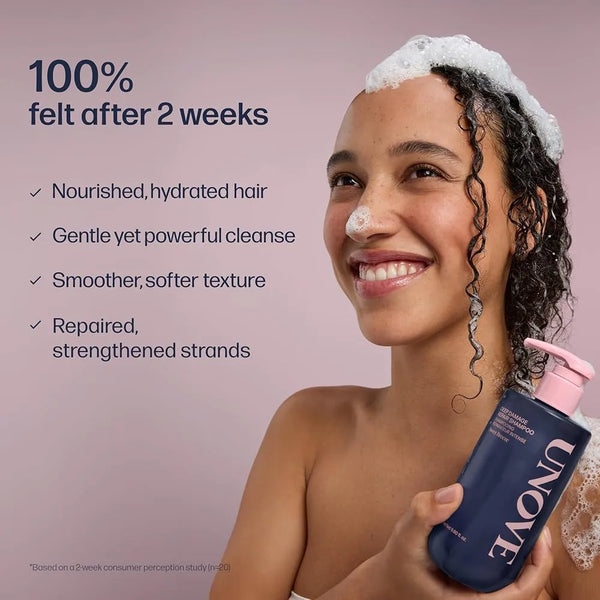 Deep damage repair shampoo bottle held by smiling person, dark navy with pink pump