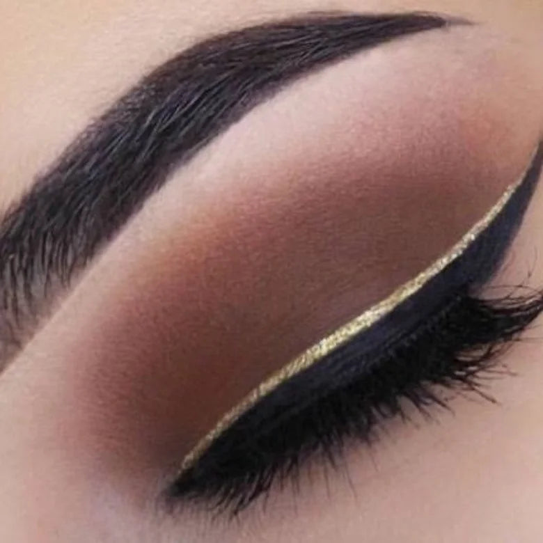 dramatic black and gold glitter cut crease eye makeup look with winged liner and bold brows