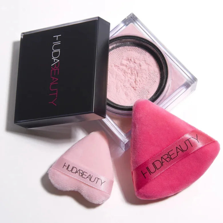 Huda Beauty Easy Bake Loose Setting Powder open jar in light pink shade with two triangle powder puffs and black box packaging