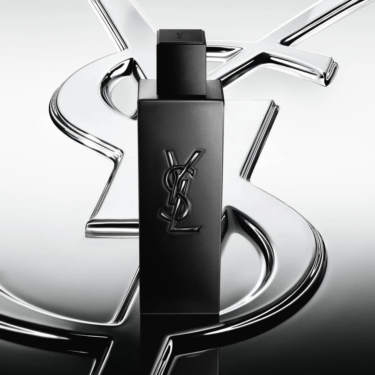 Black YSL perfume bottle on a reflective silver background